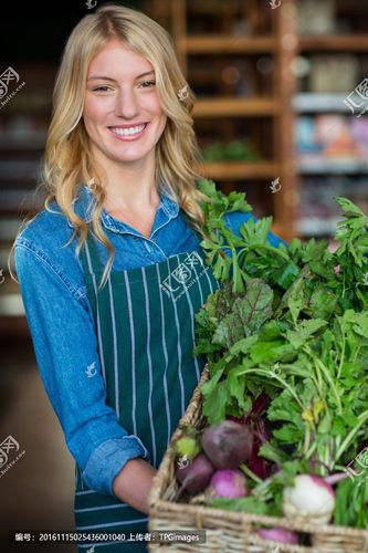 微笑的女员工在有机区拿着一篮新鲜蔬菜